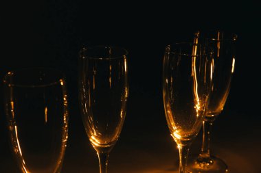 Birkaç şampanya kadehinden oluşan bir grup, koyu bir arka plan karşısında güzelce aydınlatılıyor. Şenlikli bir kompozisyon. Metin için boşluk