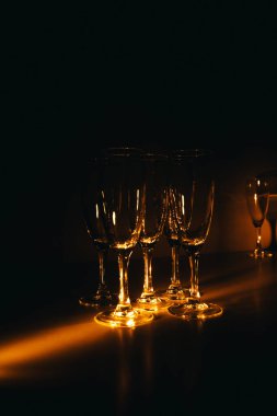 Birkaç şampanya kadehinden oluşan bir grup, koyu bir arka plan karşısında güzelce aydınlatılıyor. Şenlikli bir kompozisyon. Metin için boşluk