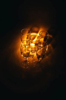 Birkaç şampanya kadehinden oluşan bir grup, koyu bir arka plan karşısında güzelce aydınlatılıyor. Şenlikli bir kompozisyon. Metin için boşluk