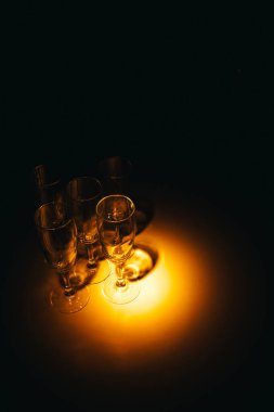 Birkaç şampanya kadehinden oluşan bir grup, koyu bir arka plan karşısında güzelce aydınlatılıyor. Şenlikli bir kompozisyon. Metin için boşluk