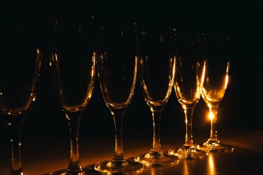 Birkaç şampanya kadehinden oluşan bir grup, koyu bir arka plan karşısında güzelce aydınlatılıyor. Şenlikli bir kompozisyon. Metin için boşluk