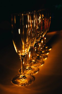 Birkaç şampanya kadehinden oluşan bir grup, koyu bir arka plan karşısında güzelce aydınlatılıyor. Şenlikli bir kompozisyon. Metin için boşluk