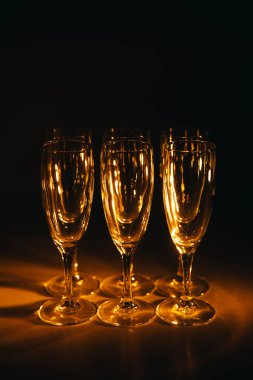 Birkaç şampanya kadehinden oluşan bir grup, koyu bir arka plan karşısında güzelce aydınlatılıyor. Şenlikli bir kompozisyon. Metin için boşluk