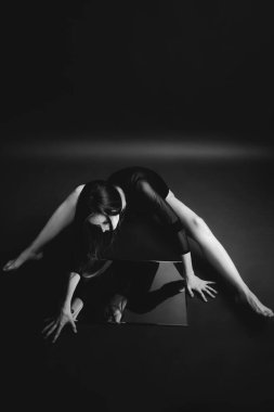 Siyah beyaz bir resim, bir kız aynaya bakar ve yansımasını görür.