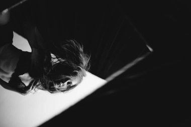 Siyah beyaz bir resim, bir kız aynaya bakar ve yansımasını görür.