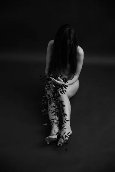 Black and white studio photo, naked girl and branch of  beautiful exotic plant on  body. Art photography, art and fashion