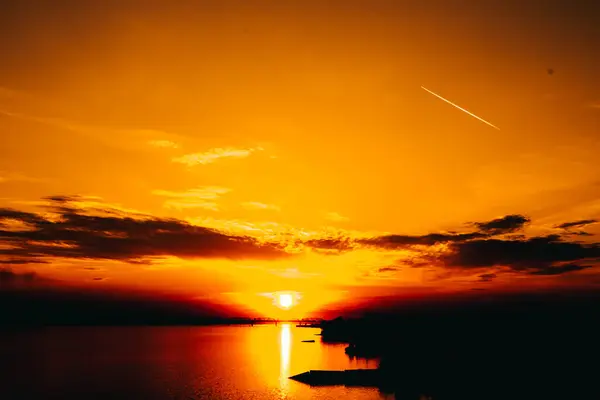 都市環境やオレンジや劇的な自然景観の中での水の上の信じられないほど美しい夕日 — ストック写真