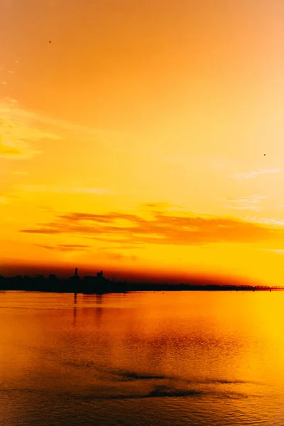 都市環境やオレンジや劇的な自然景観の中での水の上の信じられないほど美しい夕日 — ストック写真