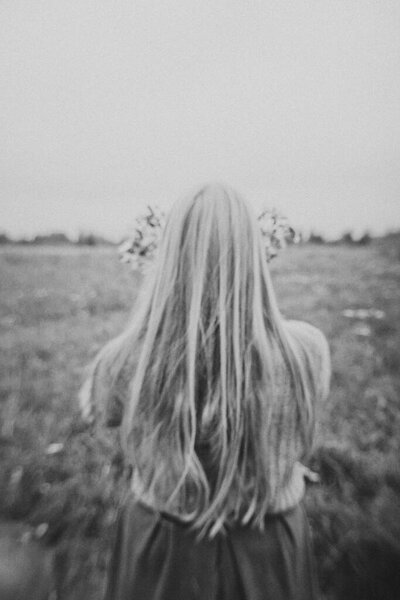 Young girl with wildflowers walks in field