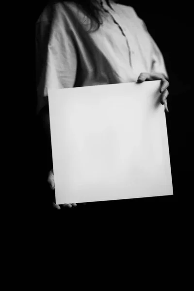 白の四角形のシートを持った薄い色のシャツを着た男の白黒写真 テキストのスペース — ストック写真