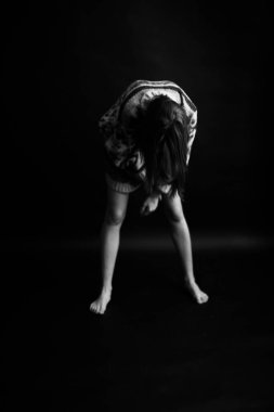 Etnik bir süslemesi olan rahat kazaklı esmer kız siyah bir arka planda özgürce poz veriyor.