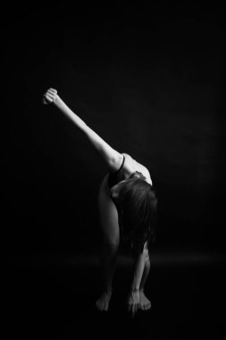 Siyah, beyaz, otantik, ince bir dansçının siyah bir vücut giysisi içindeki fotoğrafı. Stüdyo yazarının fotoğrafı. sıra dışı minimalist pozlar