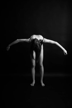 Siyah, beyaz, otantik, ince bir dansçının siyah bir vücut giysisi içindeki fotoğrafı. Stüdyo yazarının fotoğrafı. sıra dışı minimalist pozlar