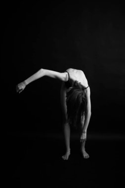 Siyah, beyaz, otantik, ince bir dansçının siyah bir vücut giysisi içindeki fotoğrafı. Stüdyo yazarının fotoğrafı. sıra dışı minimalist pozlar
