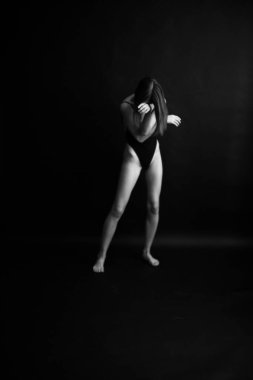 Siyah, beyaz, otantik, ince bir dansçının siyah bir vücut giysisi içindeki fotoğrafı. Stüdyo yazarının fotoğrafı. sıra dışı minimalist pozlar
