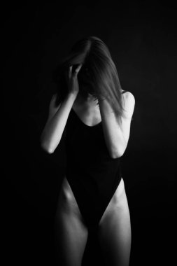 Siyah, beyaz, otantik, ince bir dansçının siyah bir vücut giysisi içindeki fotoğrafı. Stüdyo yazarının fotoğrafı. sıra dışı minimalist pozlar