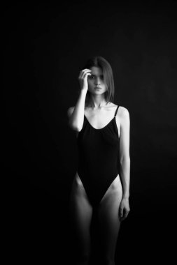 Genç bir kızın yüzünde hüzün ve hayal kırıklığı vardı. Stüdyodaki karanlık bir arka planda yüz ifadelerinin siyah-beyaz otantik portresi.