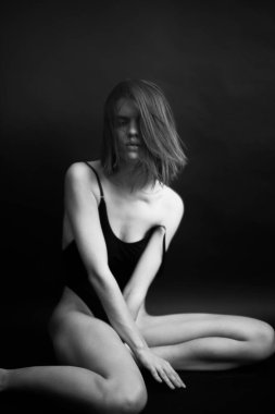 Genç bir kızın yüzünde hüzün ve hayal kırıklığı vardı. Stüdyodaki karanlık bir arka planda yüz ifadelerinin siyah-beyaz otantik portresi.