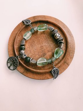 El yapımı bilezik, doğal taşlar ve kristaller, bileğinde mücevherler. Parçaların ve aksesuarların makro fotoğrafçılığı. Metin için boşluk.