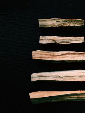 Palo Santo ağacının dağılmış dalları karanlık bir arka planda. Üst Manzara. Latin Amerika 'dan organik kutsal ağaç tütsüsü. Doğal tütsü renginde yakın plan fotoğraf.