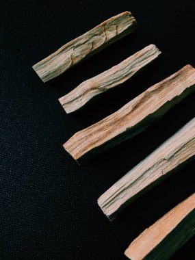 Palo Santo ağacının dağılmış dalları karanlık bir arka planda. Üst Manzara. Latin Amerika 'dan organik kutsal ağaç tütsüsü. Doğal tütsü renginde yakın plan fotoğraf.