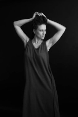 Siyah beyaz güzel bir kızın siyah beyaz portresi. Siyah uzun elbiseli, siyah örgülü saçlı, moda pozlu ve fotoğraf çekiminde doğal vücut hareketleri olan.