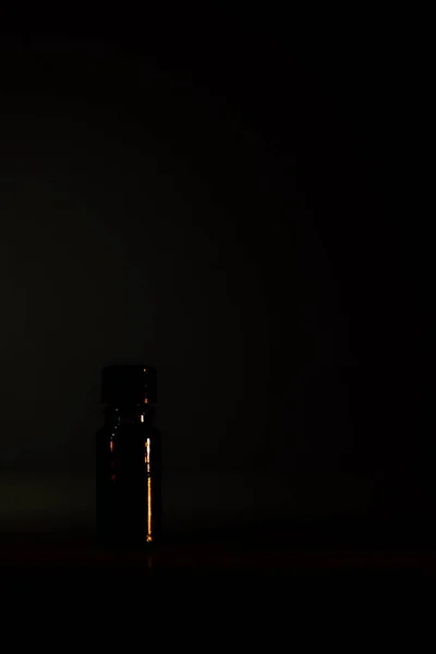 One brown bottles of cosmetics on a natural dark background. Front view.