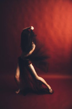 Burgundy iç çamaşırlı kız dansçının soyut portresi, kırmızı arka planda bulanık film çekimi.