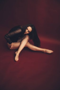 Kırmızı arka planda siyah dantelli vücutlu dansçı kızın soyut portresi. Bulanık film fotoğrafı