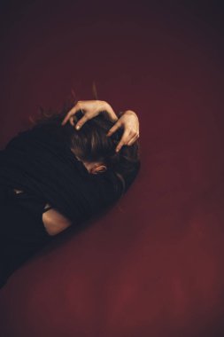 Rastalı genç manken fotoğraf stüdyosunda aktif olarak dans eder ve hareket eder. Arka plan şarap rengi ve sıcak dans rengidir.