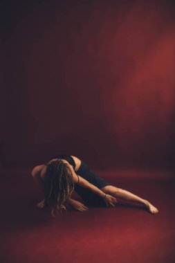 Rastalı genç manken fotoğraf stüdyosunda aktif olarak dans eder ve hareket eder. Arka plan şarap rengi ve sıcak dans rengidir.