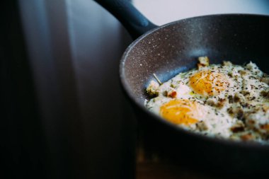 Kızartma tavasında kızarmış yumurta, peynir ve tavuk, bir kafe ve restoranda şık yemekler.