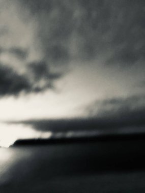 Nehir üzerindeki bir köprünün siyah beyaz fotoğrafı, karanlık şehir manzarası.