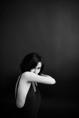 Kadının duygusal portresi, siyah elbiseli genç kız kameranın önünde duygularını ifade ediyor. Genç bir kadının gerçek üstü portresi.