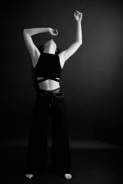 Kıvırcık bir esmerin basit ve şık portresi, kameraya ücretsiz poz, siyah yumuşak odak