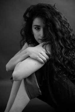 A sensual black and white portrait of a brunette girl with curly hair.