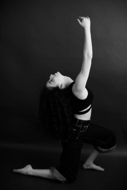 Kıvırcık bir esmerin basit ve şık portresi, kameraya ücretsiz poz, siyah yumuşak odak