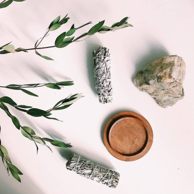 the layout of incense on a neutral background. palo santo and white sage, eucalyptus leaves and wooden stand