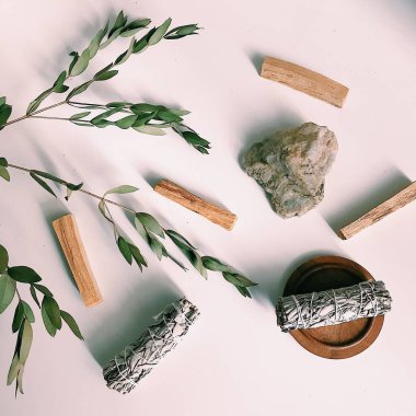 the layout of incense on a neutral background. palo santo and white sage, eucalyptus leaves and wooden stand