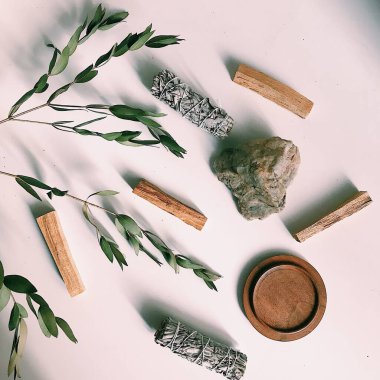 the layout of incense on a neutral background. palo santo and white sage, eucalyptus leaves and wooden stand