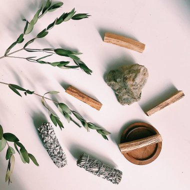 the layout of incense on a neutral background. palo santo and white sage, eucalyptus leaves and wooden stand