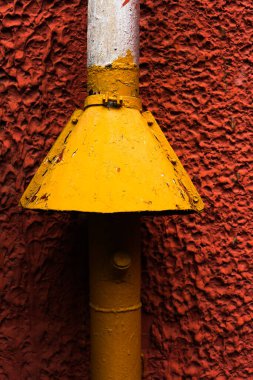 Kırmızı duvardaki sarı boru, soyut şehir arka planı