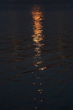 Mavi deniz yüzeyinde batan güneşin parlaklığı.