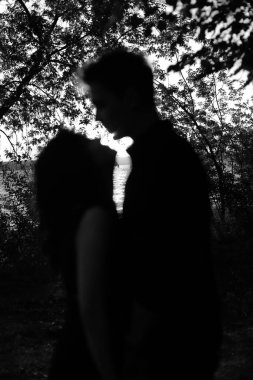 Bir erkek ve bir kadının soyut siluetleri, güneş ışınları vücutlar arasında bulanık bir odak noktası.