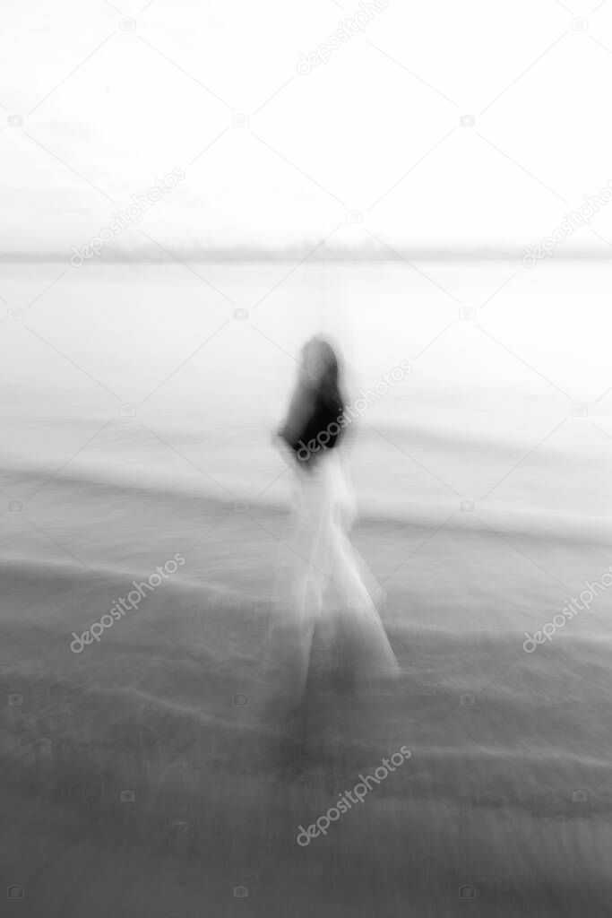 art photography, portrait by the sea, blurred silhouette of a woman and soft focus background