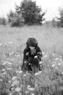 Kız çimenlerde uzanıyor, bitkilerle kucaklaşıyor. sanat siyah ve beyaz çerçeve, doğa yürüyüşü