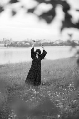 Bir kız tarlada yürüyor, siyah-beyaz bir yaz fotoğrafı, uzun bir elbise içinde doğa yürüyüşü.