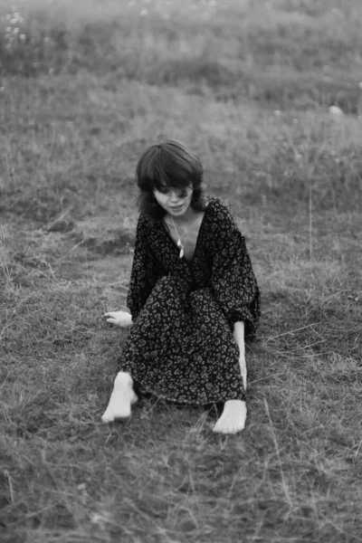 Kız çimenlerde uzanıyor, bitkilerle kucaklaşıyor. sanat siyah ve beyaz çerçeve, doğa yürüyüşü