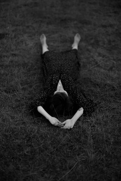 The girl is lying in the grass, embracing with plants. art black and white frame, a walk in nature