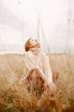 Genç kızıl saçlı bir kızın sonbahar portresi, sonbahar tarlasında bir yürüyüş.